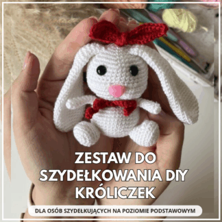Zestaw do szydełkowania DIY Króliczek – biały szydełkowy króliczek z czerwoną kokardką trzymany w dłoniach